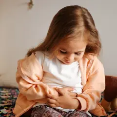 Liten flicka håller sig för magen, ser ut att ha ont i magen och diarré.