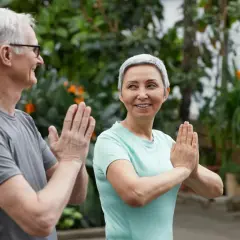 Ett äldre par ler och gör yoga utomhus. De visar att man kan leva med en lunga och njuta av livet.