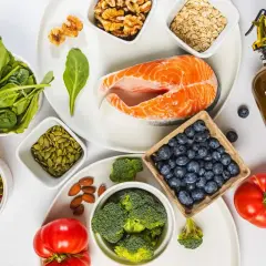 En vacker uppdukning av ingredienser för antiinflammatorisk kost: lax, bär, grönsaker, nötter och olivolja.
