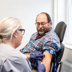 Sjuksköterska tar blodprov på man. Frågan om man kan ta blodtrycksmedicin innan provtagning är viktig för att få korrekta resultat.