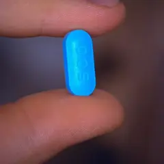 En blå tablett med siffran 500 hålls mellan fingrarna, en påminnelse om att motverka diarré vid penicillin.