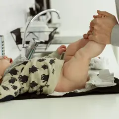 Liten bebis med björntröja byter blöja. Magen låter och bubblar, kanske blir det diarré.