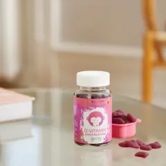 D-vitamin jordgubbssmak för barn, perfekt för vintermörkret. En flaska med björnsformade geléhallon och en liten rosa skål.