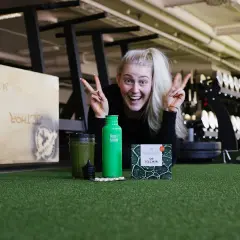 Glad kvinna med energi i gymmet, redo att ta sig an dagen. Frågan är: hur blir man pigg? Kanske med en grön smoothie och kosttillskott?
