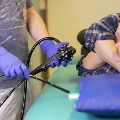 Läkare med blå handskar förbereder en endoskopi på en patient.
