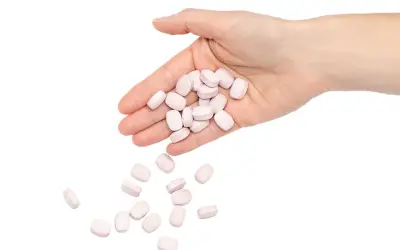 En hand håller rosa tabletter, som kan symbolisera nackdelar med betablockerare.