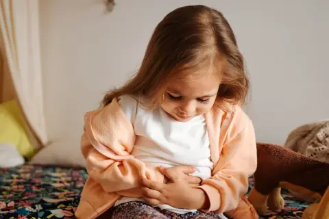 Liten flicka håller sig för magen, ser ut att ha ont i magen och diarré.
