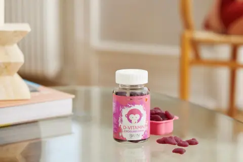 D-vitamin jordgubbssmak för barn, perfekt för vintermörkret. En flaska med björnsformade geléhallon och en liten rosa skål.