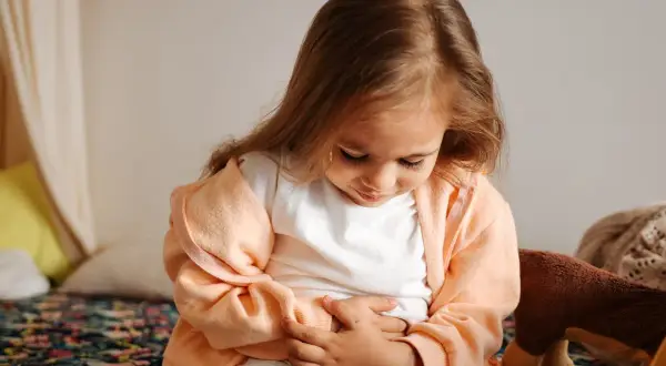 Liten flicka håller sig för magen, ser ut att ha ont i magen och diarré.