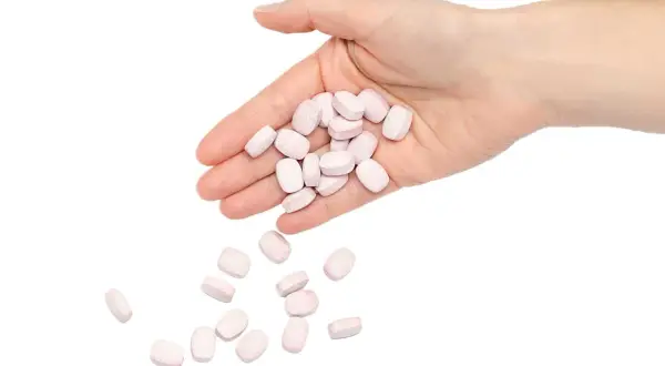 En hand håller rosa tabletter, som kan symbolisera nackdelar med betablockerare.