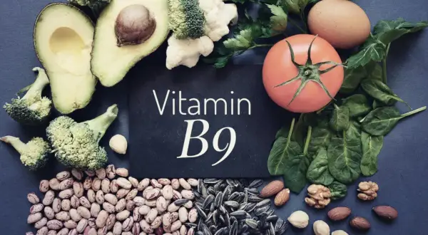 En tavla med texten "Vitamin B9" omgiven av matvaror som broccoli, avokado, bönor, solrosfrön, nötter, spenat, tomat och ägg.
