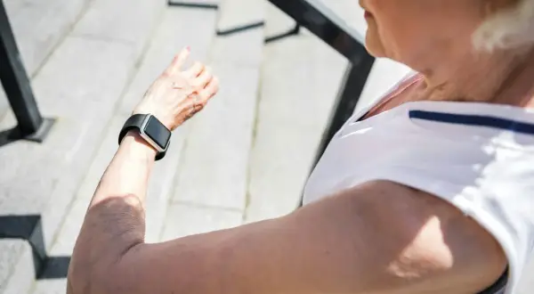 Äldre kvinna kollar sin smartklocka, som kan användas för långtids ekg, efter ett träningspass utomhus.