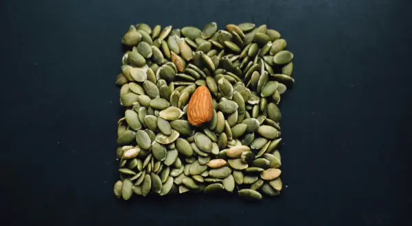 En ensam mandel bland pumpafrön. Kan vara en visuell metafor för e-vitamin brist symptom, då frön är rika på vitamin E.