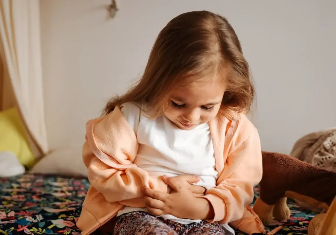 Liten flicka håller sig för magen, ser ut att ha ont i magen och diarré.
