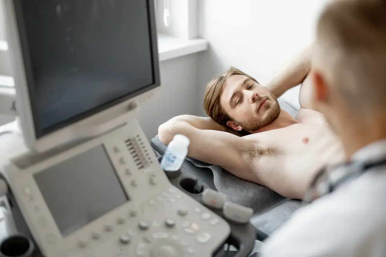 Man undersöks med ultraljud, orolig för en knuta på halsen. Läkaren tittar på skärmen.