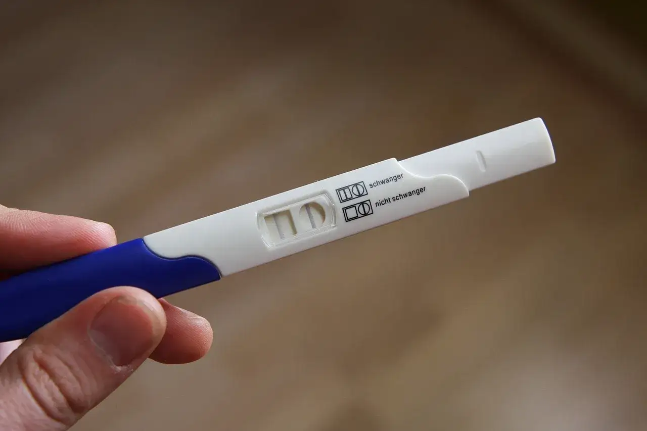 Graviditetstest visar tv&aring; streck, positivt resultat. En person h&aring;ller testet, kanske gravid utan symtom.