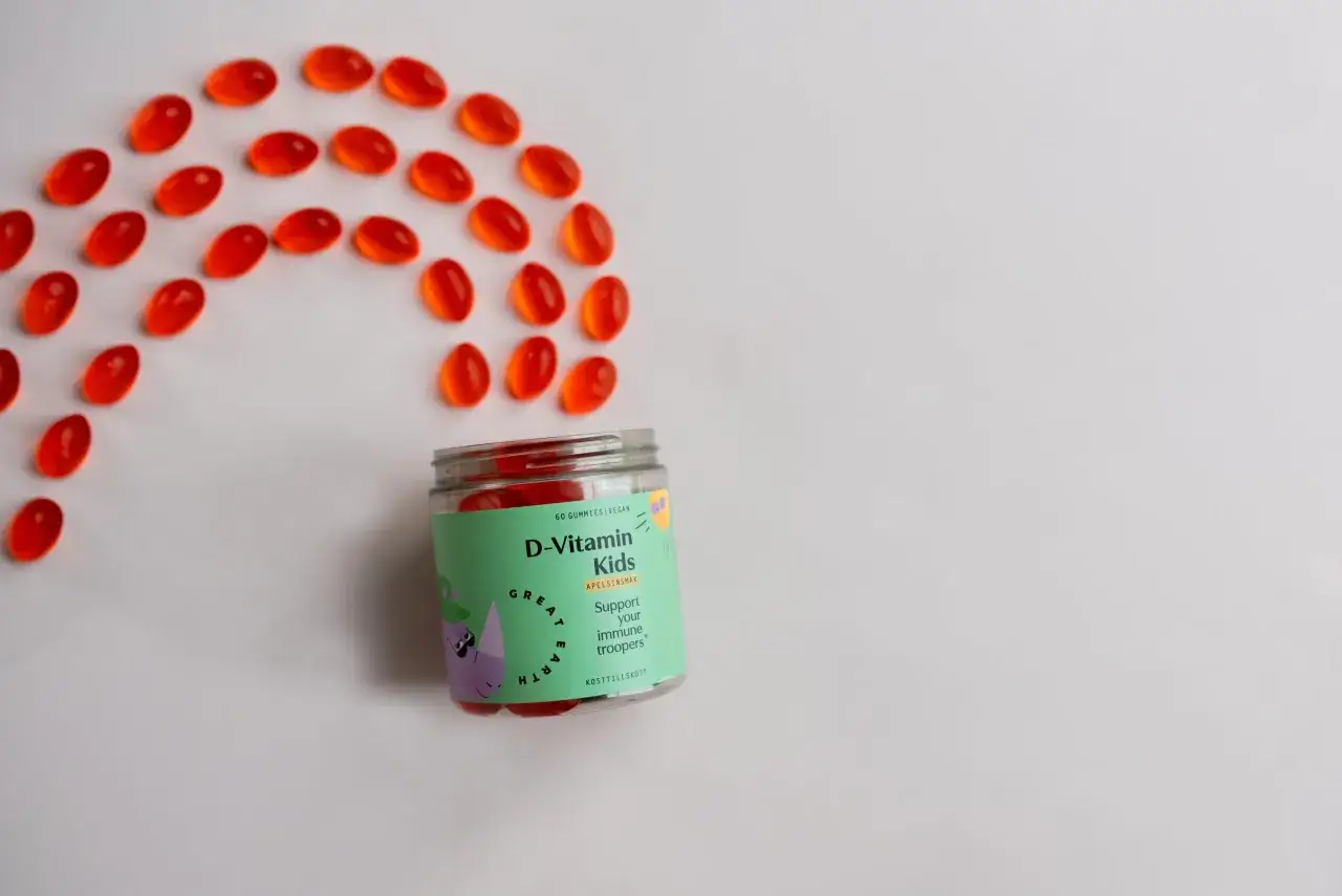 R&ouml;da D-vitamin gummies f&ouml;r barn ligger utspridda som en b&aring;ge bredvid burken. Perfekt f&ouml;r sm&aring; immunf&ouml;rsvar!