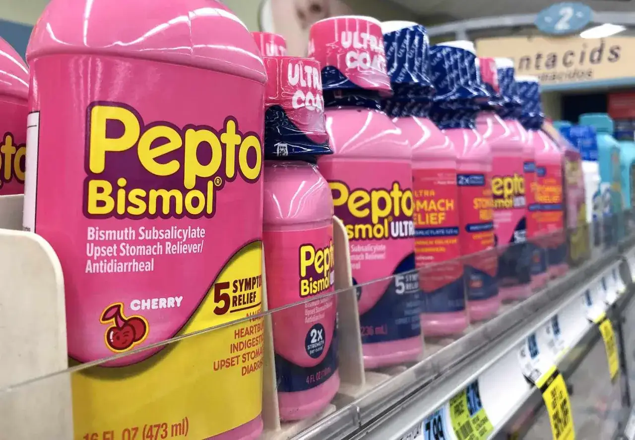 Rader av rosa flaskor med Pepto-Bismol, ett effektivt medicin mot diarr&eacute; och oroliga magar, st&aring;r uppradade p&aring; en hylla i en butik.