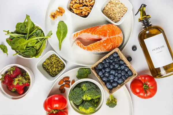 En vacker uppdukning av ingredienser för antiinflammatorisk kost: lax, bär, grönsaker, nötter och olivolja.