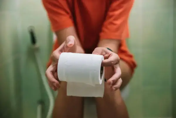 Person håller toalettrulle, kanske för att lindra besvär med ett snabbverkande laxermedel.